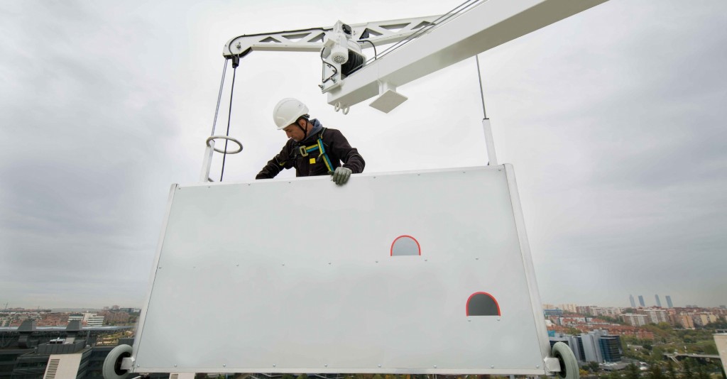 Technician on a suspended access platform above a city skyline