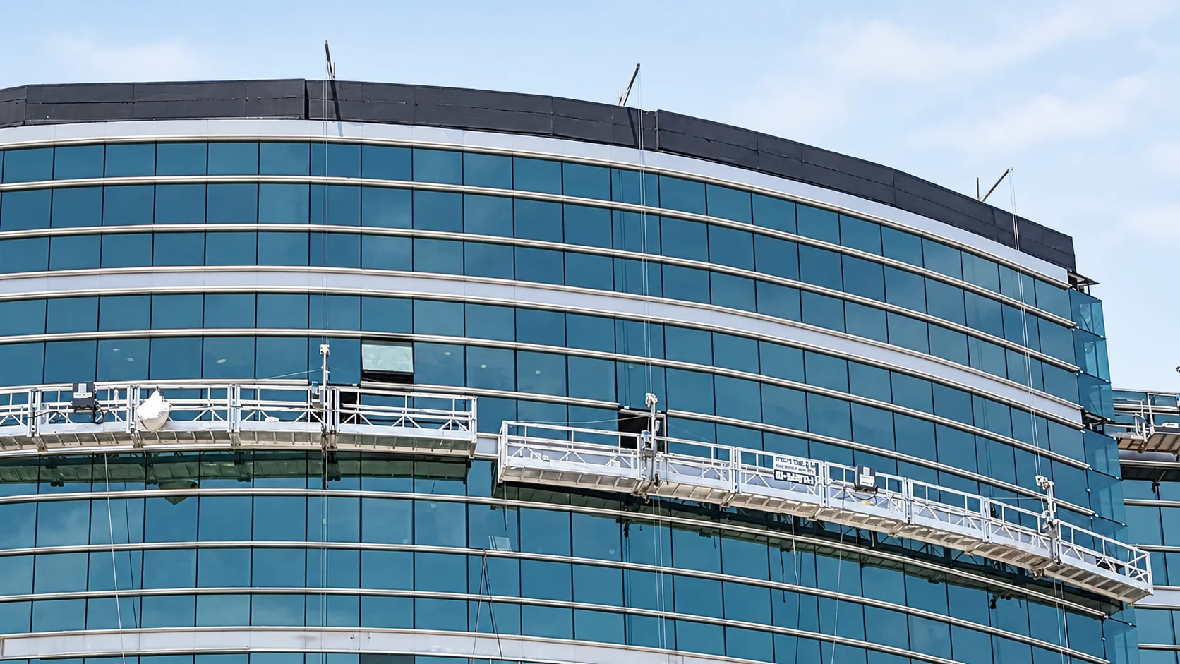 Suspended platforms on a curved glass facade.