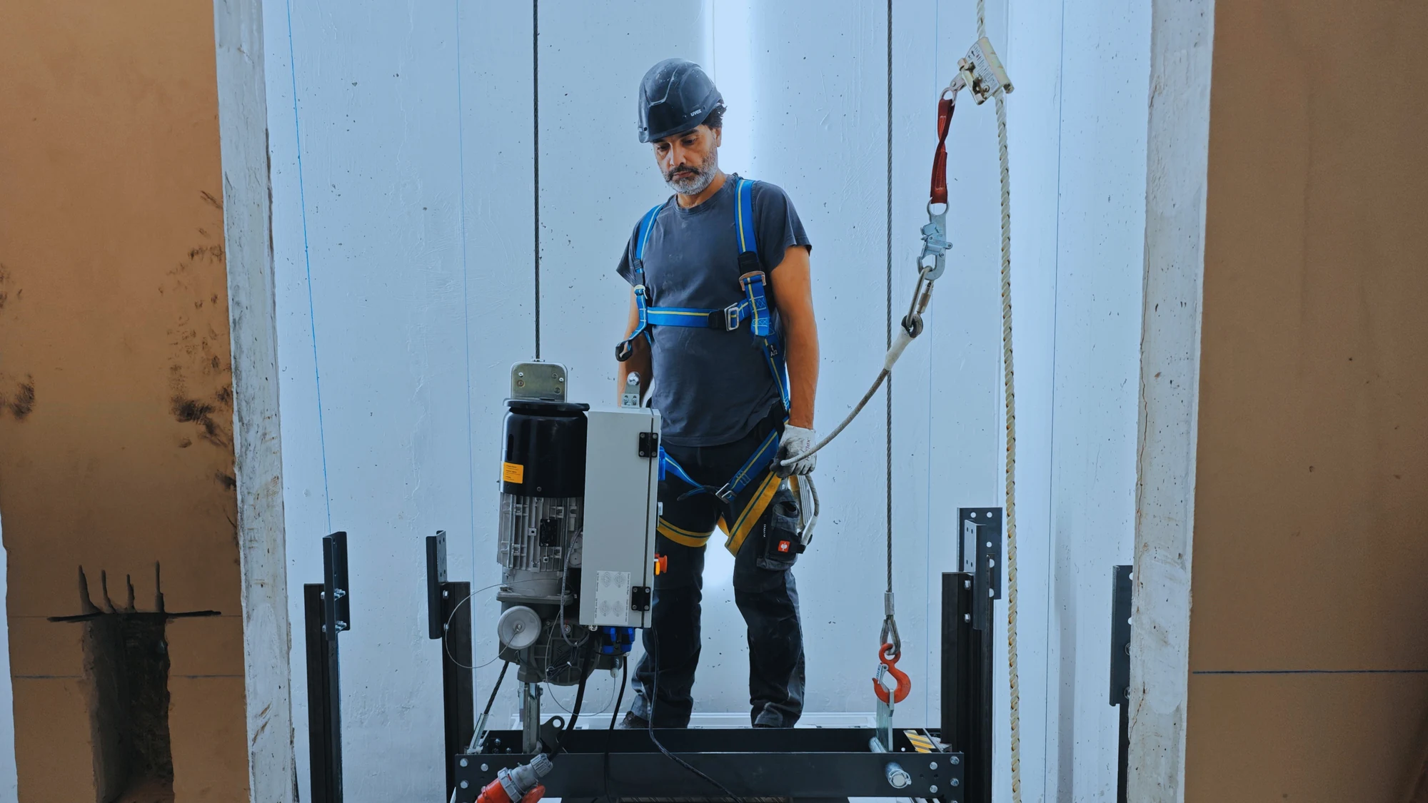 Technician with a traction hoist on a platform during installation.